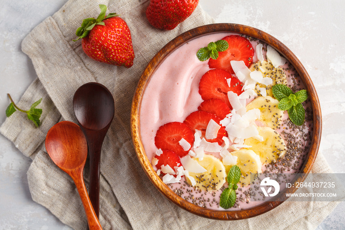 Strawberry pink smoothie bowl with banana, coconut and chia seeds, top view. Healthy vegan food concept.