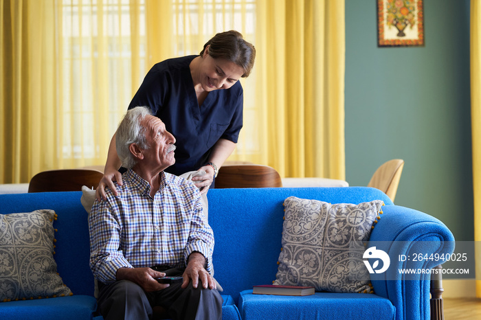 Professional helpful caregiver and a senior man during home visit