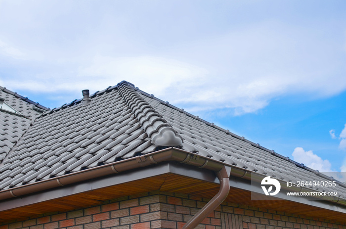 Dark brown ceramic tile roof against blue sky.