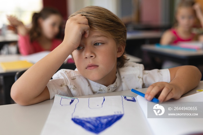 Sad schoolboy studying in classroom sitting at desks in school