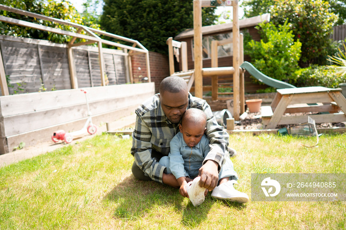 Father with Down syndrome helping son (2-3) put on shoe