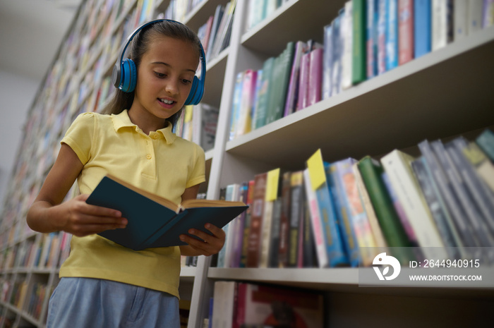 Girl in headphones reading a book in the library