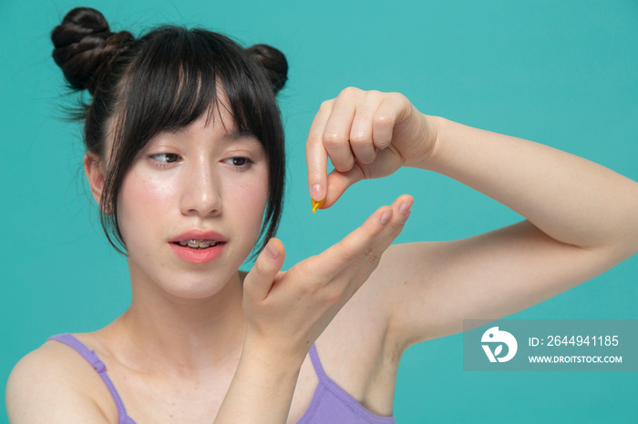 Studio portrait of girl dropping serum on hand