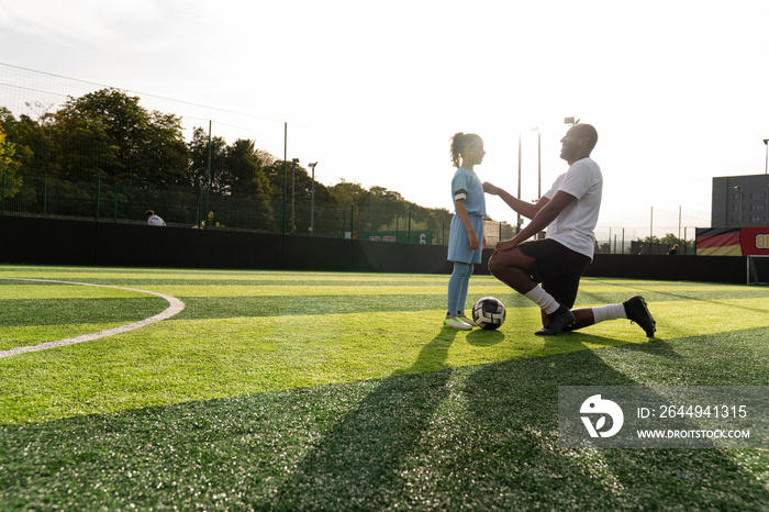 Coach and girl (6-7) on soccer field