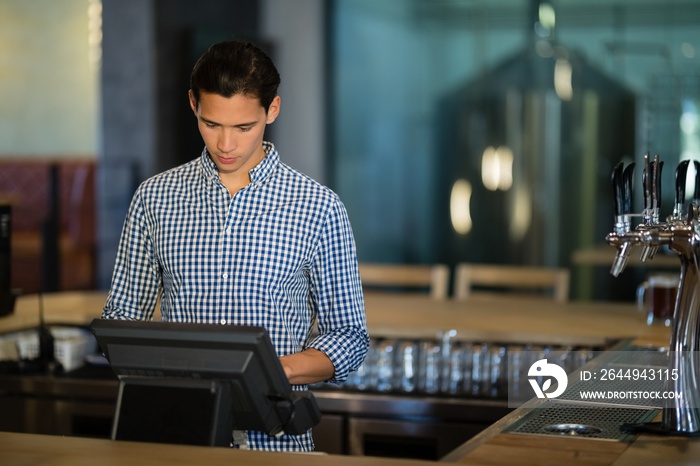 Bar tender operating cash desk at counter