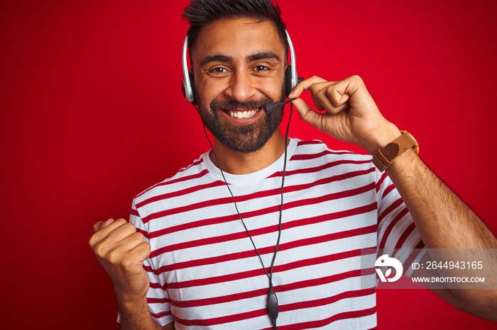 Young indian call center agent man using headset over isolated red background screaming proud and celebrating victory and success very excited, cheering emotion