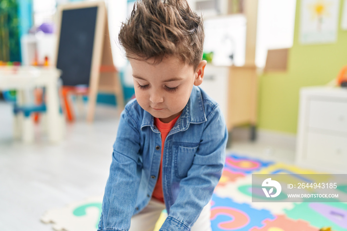 Adorable hispanic toddler standing with relaxed expression at kindergarten