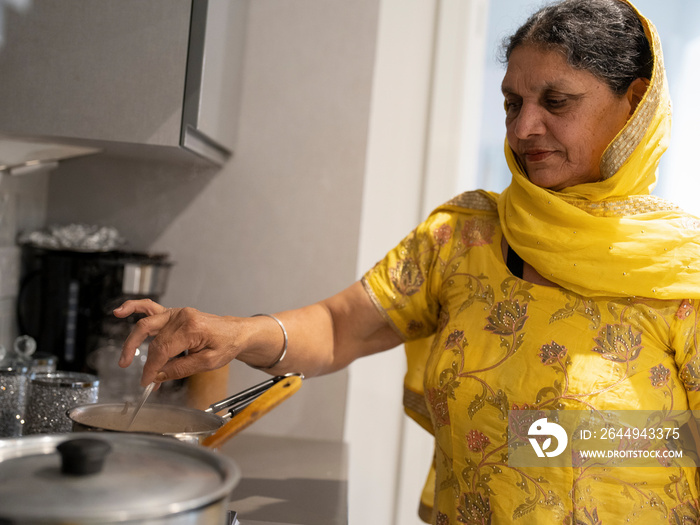 Mature woman in traditional clothing cooking meal