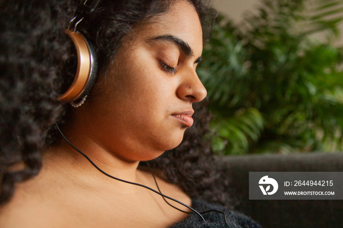 Close up portrait of curvy Indian girl with Cerebral Palsy with headphones  in living room