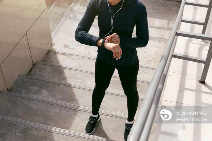 Young woman wearing sports clothing looking at activity tracker