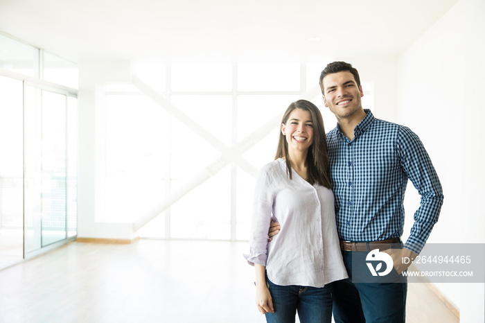 Smiling Couple Standing Arm Around In New Home