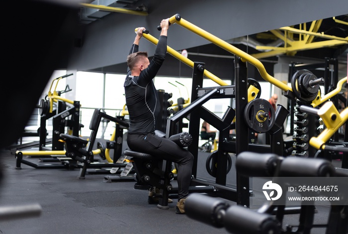 A healthy, fit bodybuilder is exercising with equipment in the gym. Daily trening.