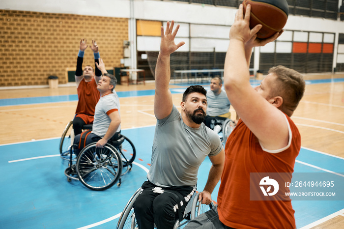 Basketball player in wheelchair trying to block opponent player to take a shot during the match.