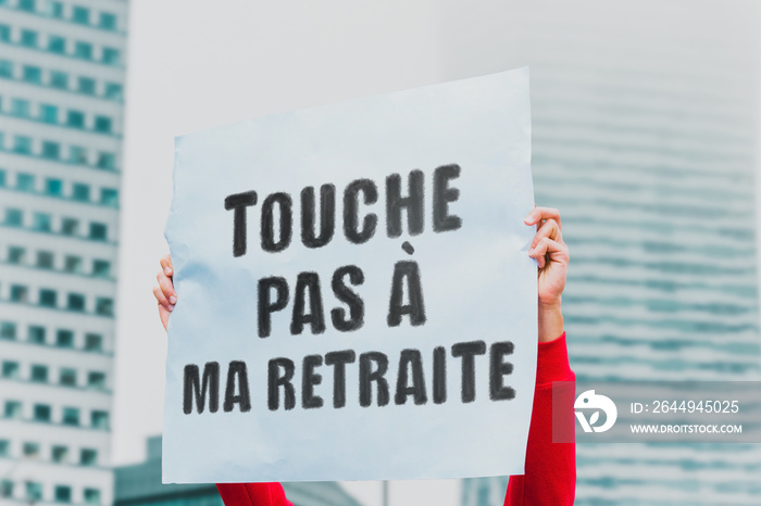 The phrase   Touche  pas à  ma retraite   on a paper banner in men’s hand. Human holds a cardboard with an inscription. Politics. Protest. Social Issue. Pension. France