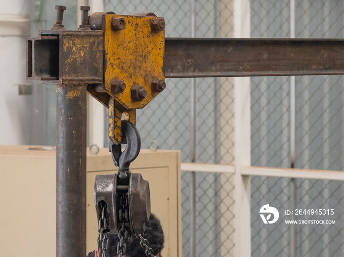 The brown steel hoist is suspended on a movable yellow steel box rail. which is used to help lift heavy objects, use in industrial plants, safety