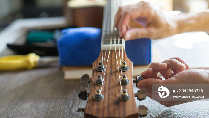 Checking the acoustic guitar string, Expert is tuning the guitar string, Close-up