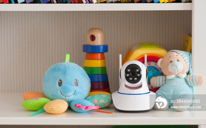 IP camera on the shelf with toys, serving as a baby monitor