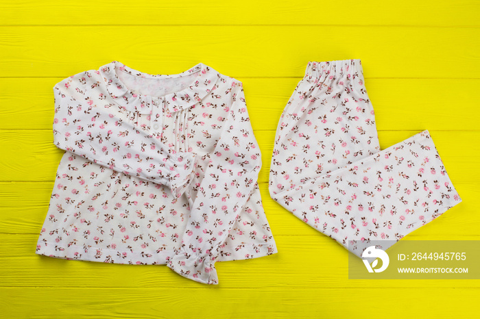 Floral top and pants on yellow table. Soft lightweight cotton for summer nights. Comfy and roomy pajama set for girls.