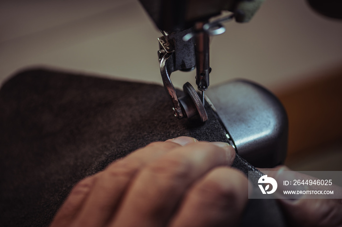 Partial view of shoemaker sewing genuine leather on sewing machine