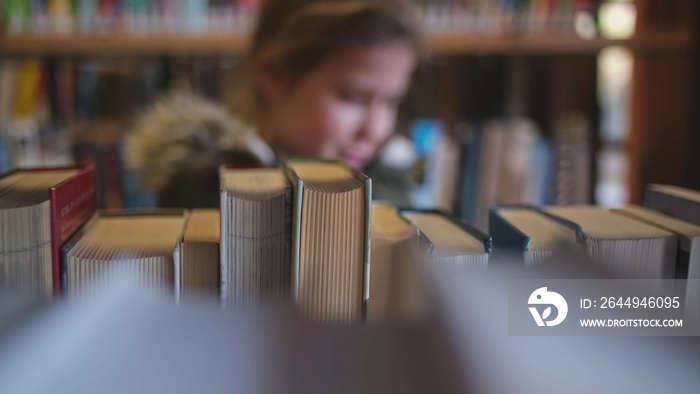 Young Intelligent Smart Caucasian Girl Looking For Interesting Book to Read in Public Library