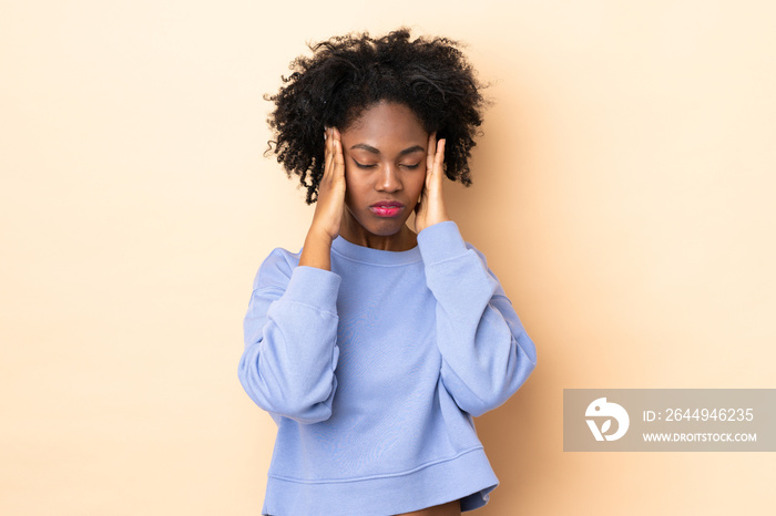 Young African American woman isolated on beige background with headache