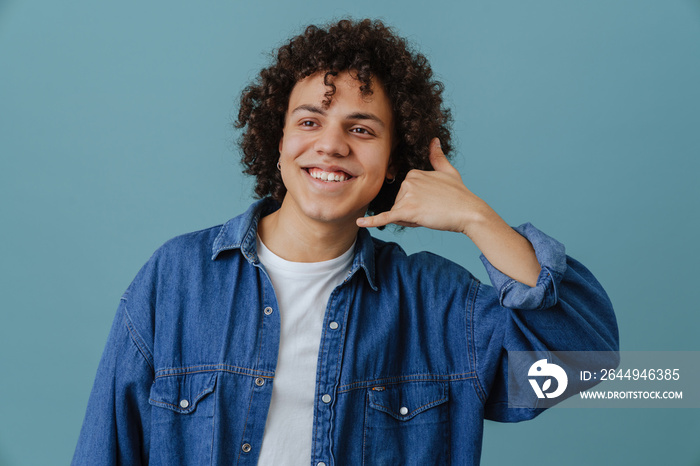 Curly young man smiling and making handset gesture