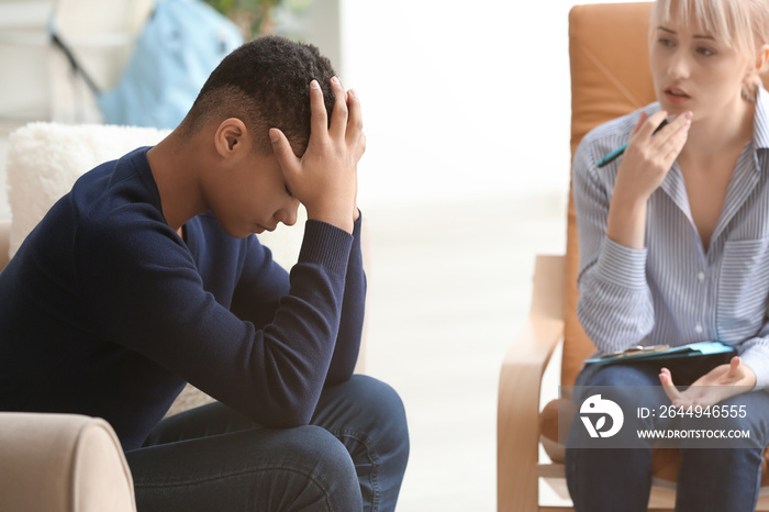 Female psychologist working with depressed teenage boy in office