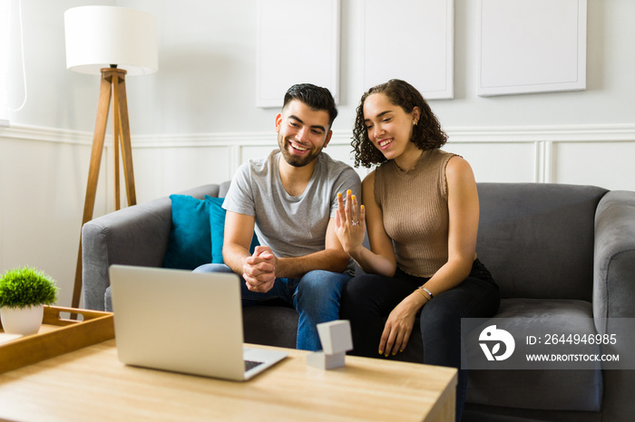 Attractive young couple getting engaged and calling their family on a video call