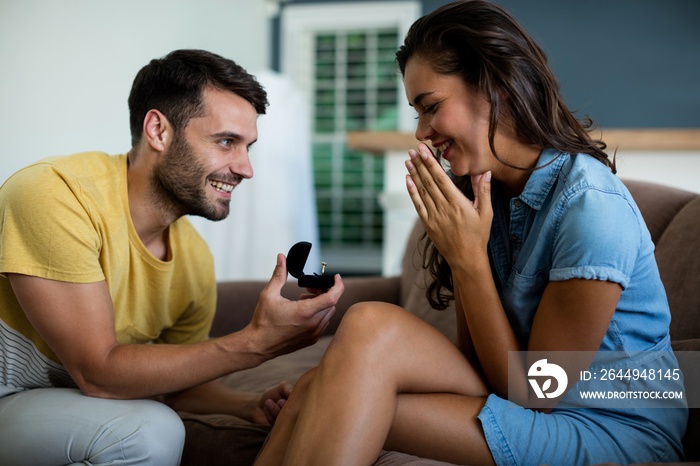 Man offering a engagement ring to woman in the living room