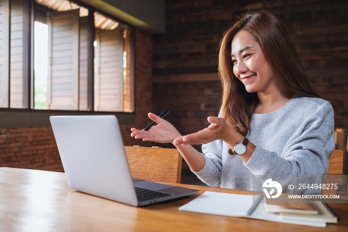 A beautiful young asian woman using laptop computer for video call and working online at home