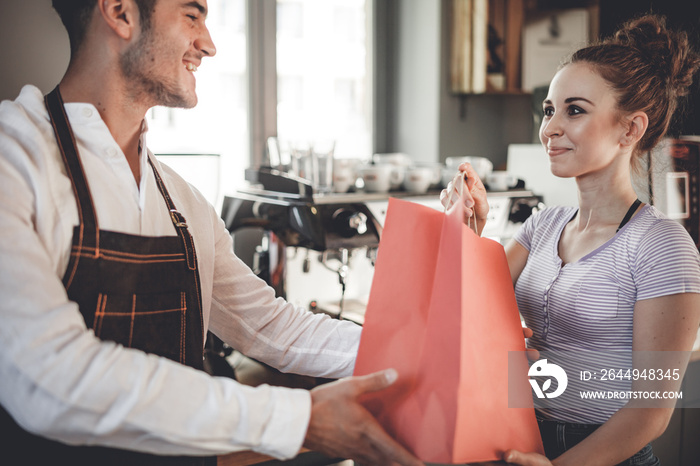 Happy customer taking paper bag after shopping at coffee shop