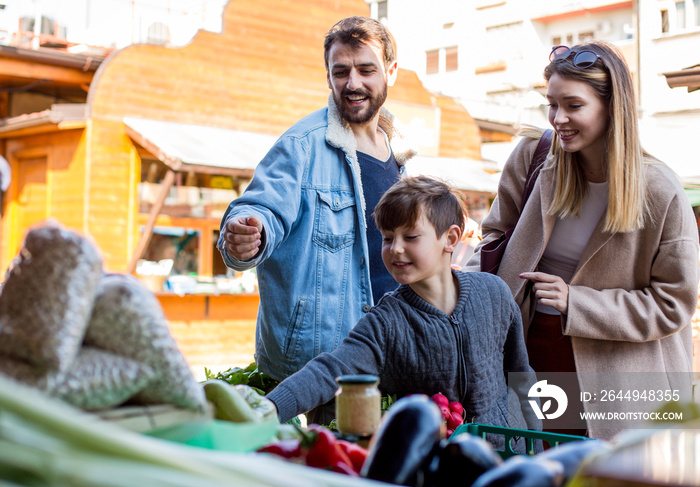 Father, mother and son in a street market buying groceries