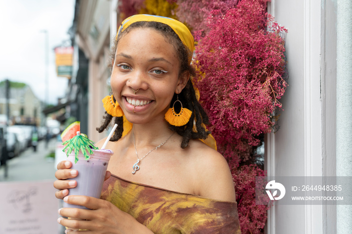 Portrait of young woman drinking smoothie in city