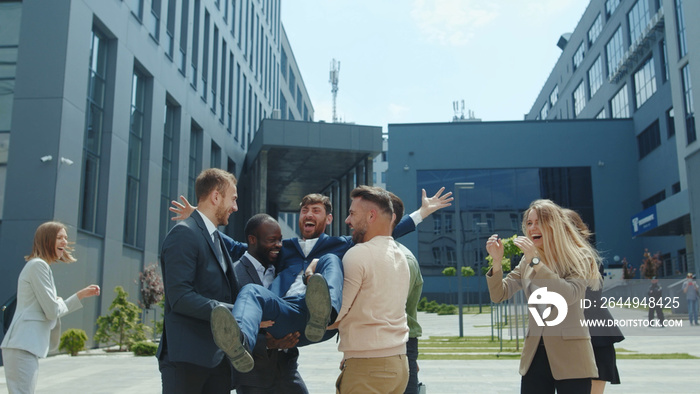 Corporate party. Multi-ethnic happy office workers colleagues business people celebrating company triump throwing their boss up in the air. Fun concept.