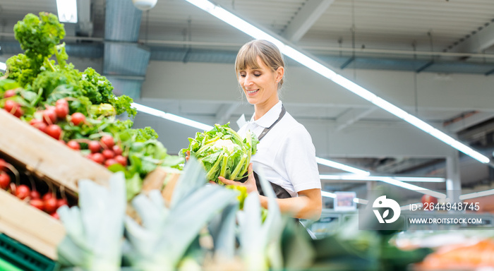 Woman working in a supermarket sorting fresh fruit and vegetables