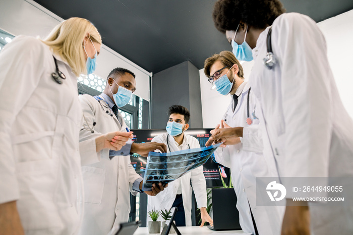 Multiethnic medical team of oncologists, radiologists and surgeons, analyzing ct scan photo in the clinic. Computed tomography of the lungs with pneumonia, coronavirus disease, covid19