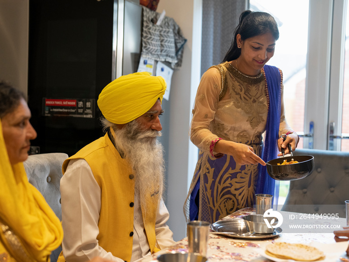 Family in traditional clothing eating meal at home