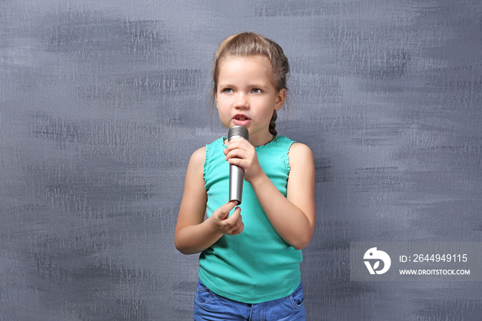 Cute little girl with microphone on color background