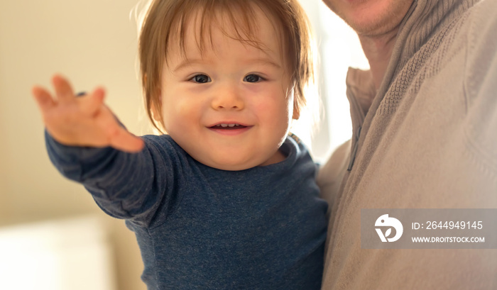 Happy toddler boy being held and cared for by his parents