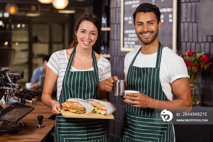 Smiling baristas holding sandwiches and hot milk