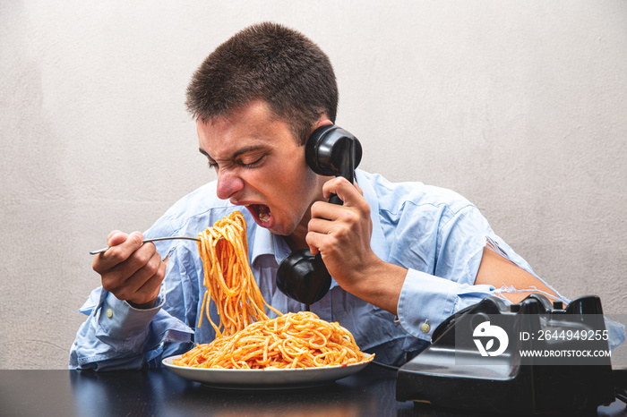 boy eating spaghetti with tomato sauce and speaking at phone