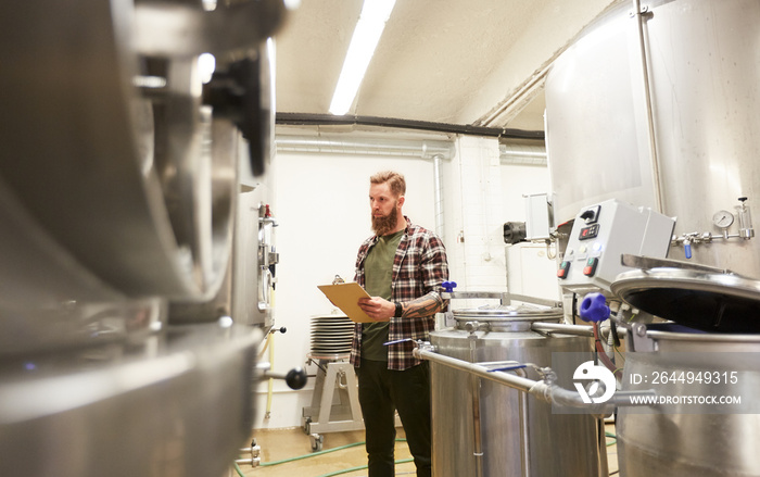 man with clipboard at craft brewery or beer plant