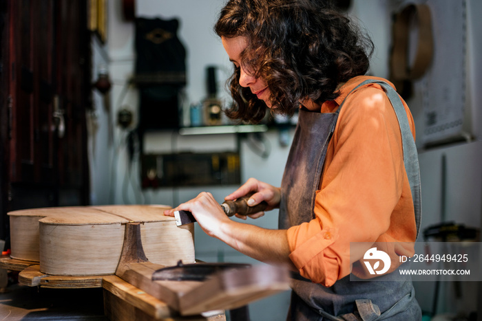 woman luthier making guitars in her musical instrument workshop