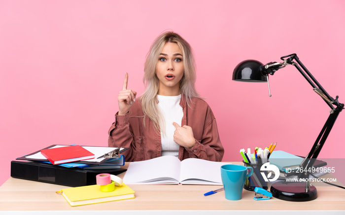 Young student woman working in a table with surprise facial expression