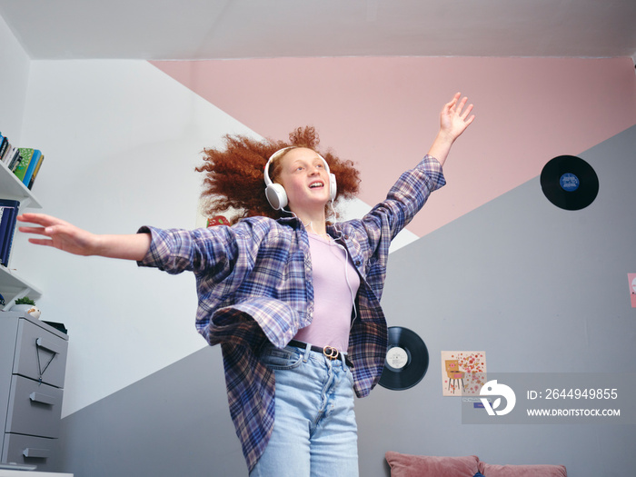 Girl wearing headphones dancing in room