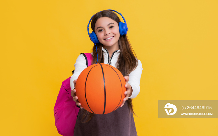 happy child in headphones with school backpack and basketball ball. selective focus