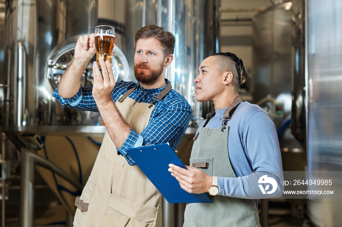 Waist up portrait of brewmaster holding beer glass