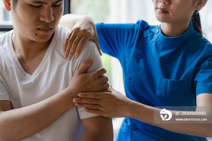 Female doctor’s hand doing physiotherapy by extending the shoulder of a male patient. Doctor or physiotherapist working examining back injury treatment of male pain therapy patient in clinic