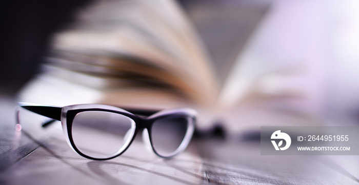 Composition with glasses and open book on the table