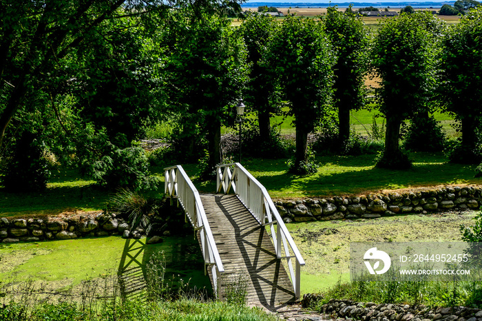 Kokkedal Slot, Denmark A little garden walkway over a moat in a garden.